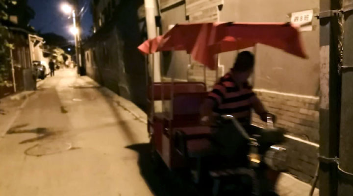 tuk tuk driver at night in a beijing hutong